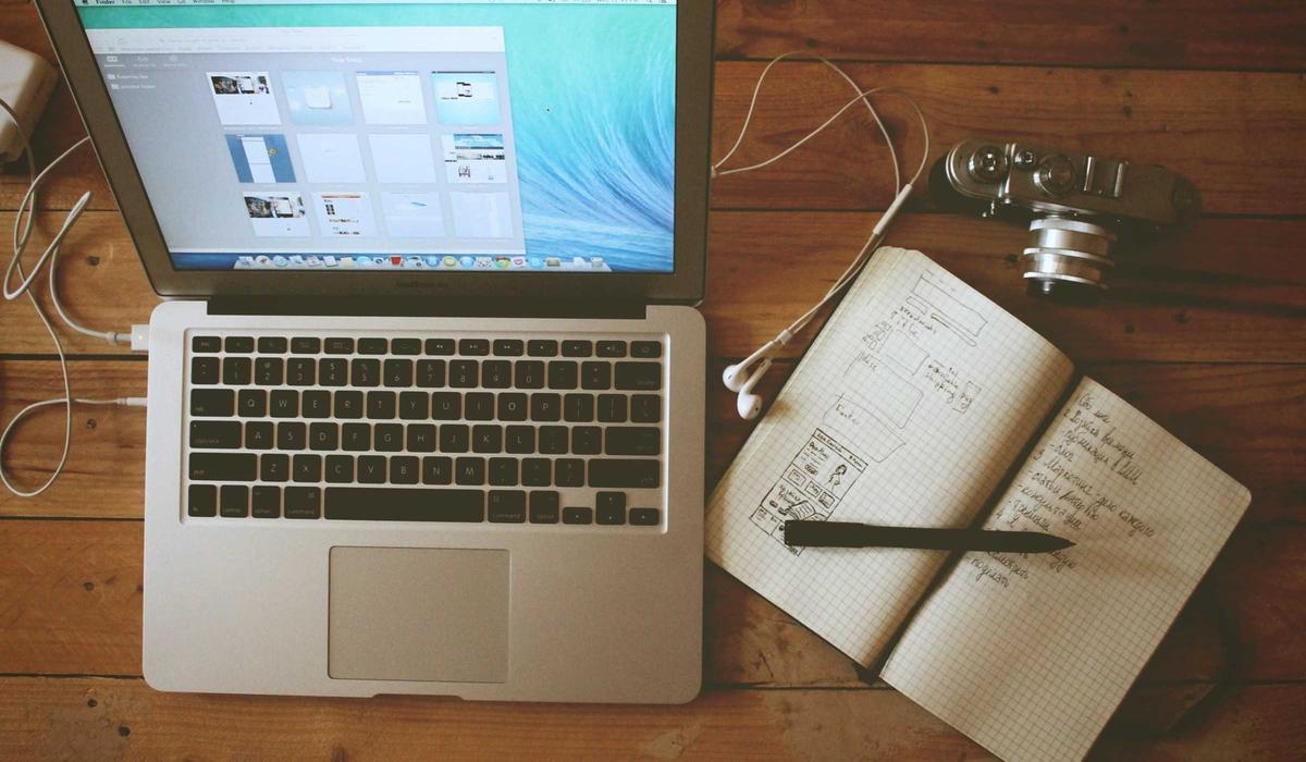 A maker’s desk: laptop, hand-drawn wireframes, and a notebook on a wooden table